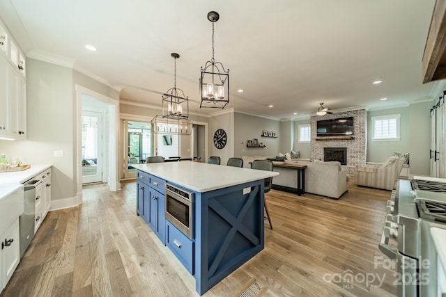 365 Delburg St, Davidson, NC 28036 - kitchen with blue cabinets, stainless steel appliances, ornamental molding, a brick fireplace, and white cabinetry