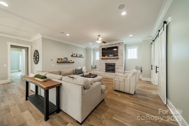 365 Delburg St, Davidson, NC 28036 - living room featuring a barn door, crown molding, light wood-style flooring, baseboards, and a fireplace