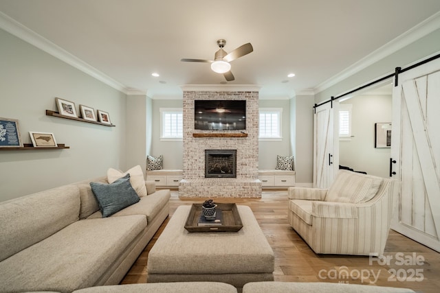365 Delburg St, Davidson, NC 28036 - living room featuring light wood-style flooring, ornamental molding, ceiling fan, healthy amount of natural light, and a barn door