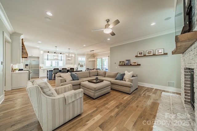 365 Delburg St, Davidson, NC 28036 - living room with ornamental molding, light wood-style floors, a chandelier, a ceiling fan, and a brick fireplace