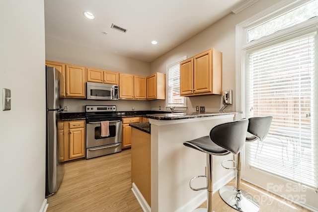 984 Park Slope Dr, Charlotte, NC 28209 - kitchen with stainless steel appliances, a peninsula, healthy amount of natural light, light brown cabinets, and recessed lighting