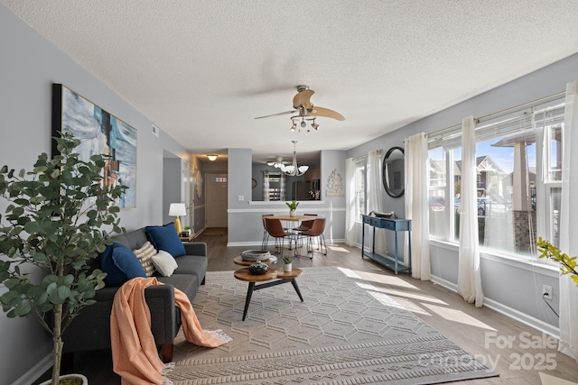 1201 Deermouse Way, Hendersonville, NC 28792 - living room with ceiling fan with notable chandelier, baseboards, wood finished floors, and a textured ceiling