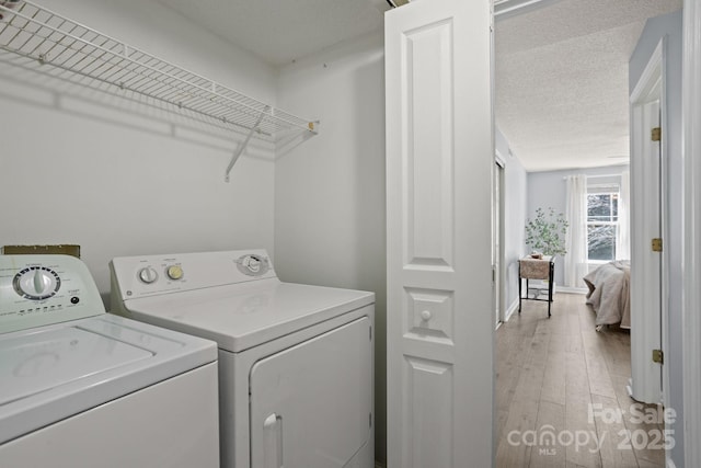 1201 Deermouse Way, Hendersonville, NC 28792 - laundry area with washing machine and clothes dryer, light wood-style flooring, a textured ceiling, and laundry area