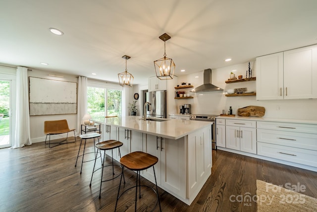 kitchen featuring open shelves, light countertops, dark wood-type flooring, wall chimney exhaust hood, and appliances with stainless steel finishes