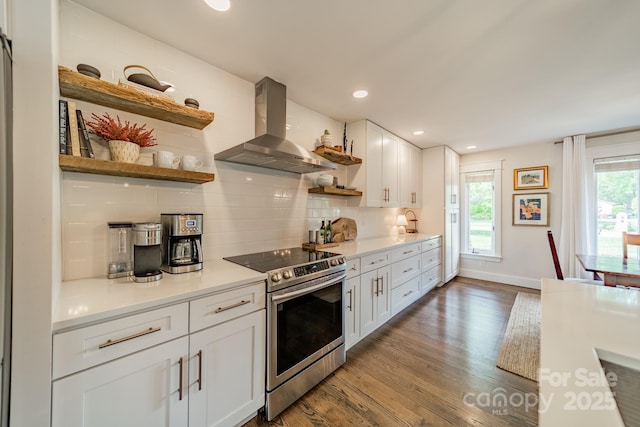 kitchen with wall chimney exhaust hood, white cabinets, wood finished floors, stainless steel range with electric stovetop, and open shelves
