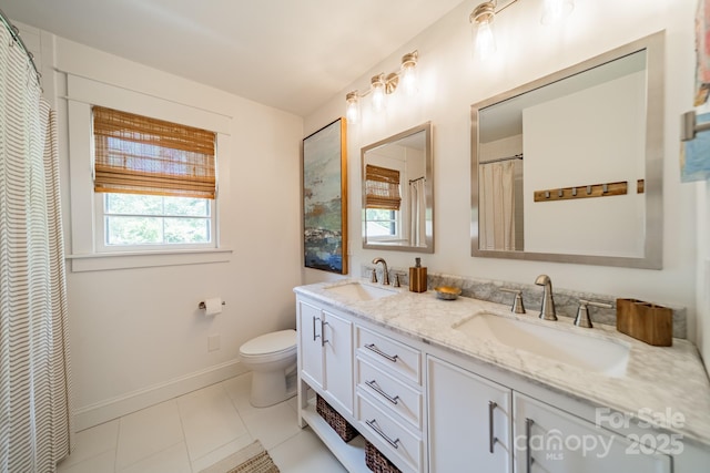 bathroom with baseboards, a sink, double vanity, and toilet