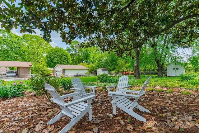 view of yard with a fire pit, a storage unit, fence, and an outdoor structure