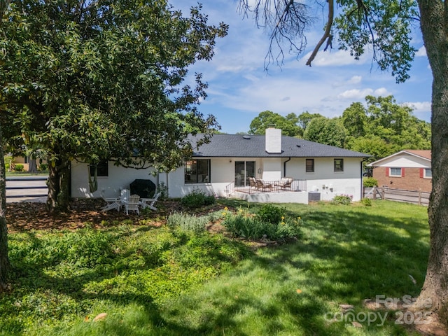 rear view of property with cooling unit, fence, a patio area, a lawn, and stucco siding