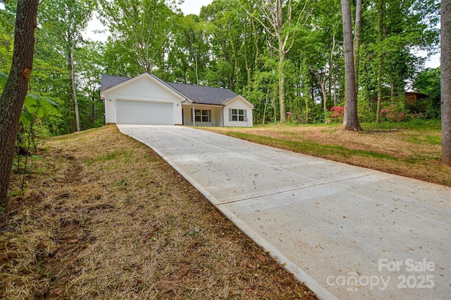 single story home featuring an attached garage, concrete driveway, and a front lawn