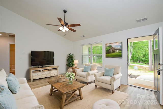 living room featuring visible vents, light wood-style flooring, ceiling fan, and lofted ceiling