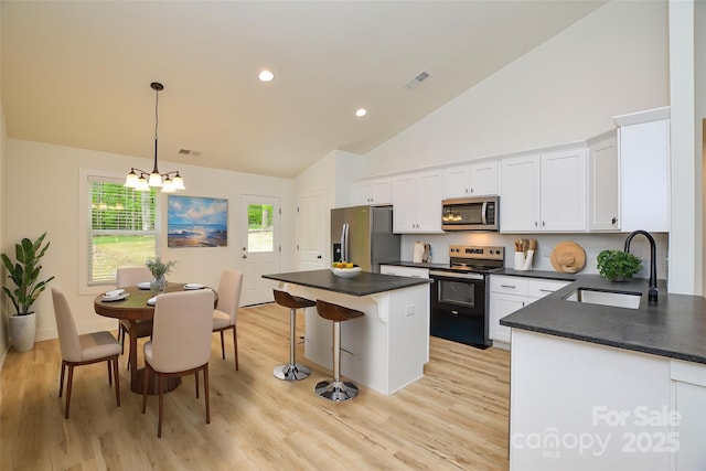 kitchen featuring dark countertops, a sink, a chandelier, stainless steel appliances, and visible vents