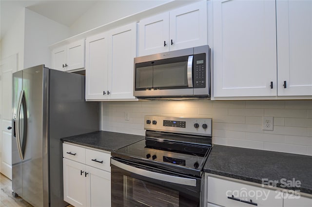 kitchen featuring white cabinets, backsplash, appliances with stainless steel finishes, and dark stone counters