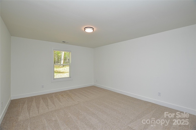 empty room with baseboards, visible vents, and light colored carpet
