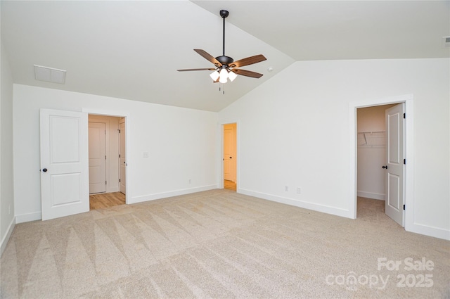 unfurnished bedroom featuring light carpet, baseboards, vaulted ceiling, a spacious closet, and visible vents