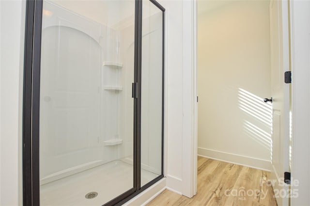 bathroom featuring baseboards, wood finished floors, and a stall shower