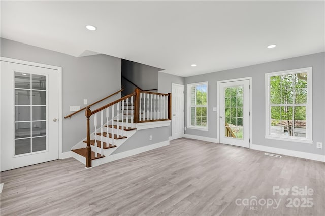 unfurnished living room featuring visible vents, baseboards, wood finished floors, and stairs