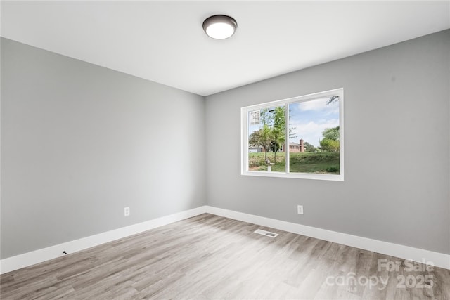 spare room featuring wood finished floors, visible vents, and baseboards