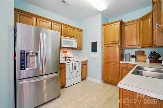 kitchen featuring light countertops, brown cabinets, white appliances, and visible vents