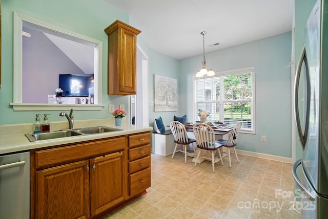 kitchen featuring a sink, light countertops, brown cabinetry, and stainless steel appliances