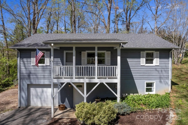 view of front facade featuring aphalt driveway, covered porch, a shingled roof, and a garage