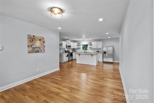 4009 Dunwoody Dr, Charlotte, NC 28215 - kitchen with open shelves, appliances with stainless steel finishes, a breakfast bar area, white cabinetry, and baseboards