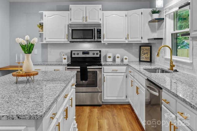 4009 Dunwoody Dr, Charlotte, NC 28215 - kitchen with stainless steel appliances, a sink, open shelves, white cabinetry, and light wood-type flooring