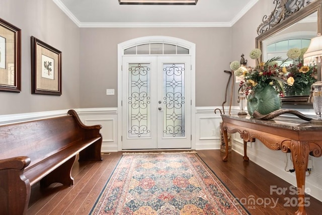 foyer entrance featuring a wainscoted wall, ornamental molding, french doors, a decorative wall, and hardwood / wood-style flooring