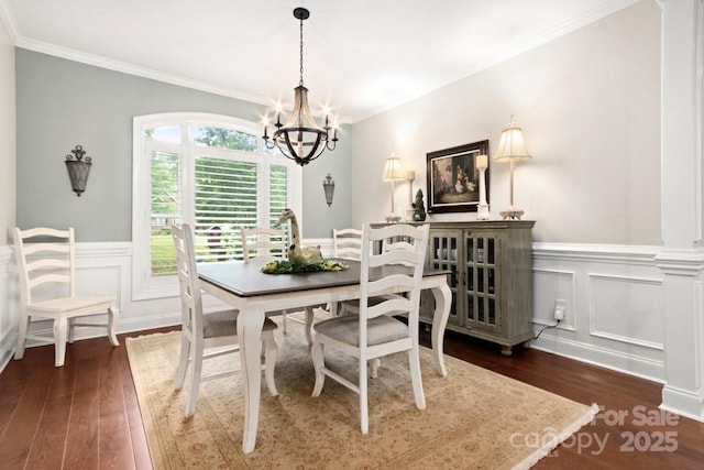 dining space featuring a decorative wall, crown molding, dark wood-style floors, and a notable chandelier