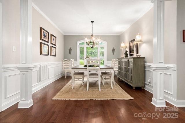dining room featuring dark wood finished floors, a decorative wall, and ornate columns