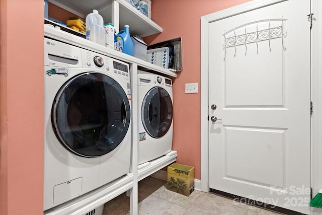 clothes washing area with baseboards, washer and dryer, and laundry area