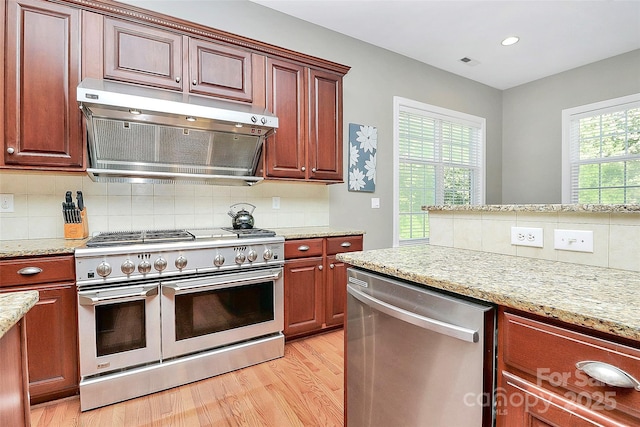 1105 Hoyle Ln, Waxhaw, NC 28173 - kitchen with light wood-type flooring, appliances with stainless steel finishes, backsplash, under cabinet range hood, and visible vents