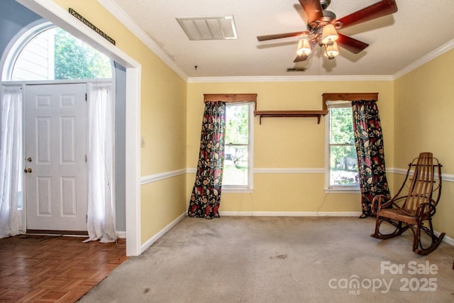 foyer featuring baseboards, crown molding, and visible vents