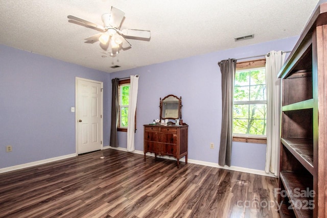 unfurnished bedroom with a textured ceiling, wood finished floors, visible vents, and multiple windows