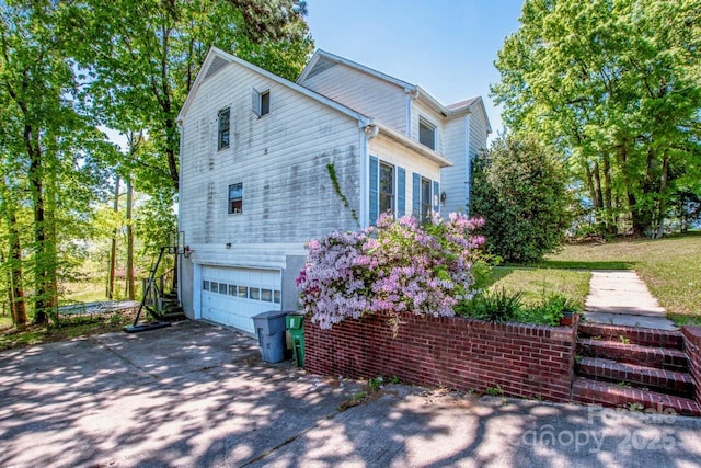 view of property exterior featuring an attached garage and driveway