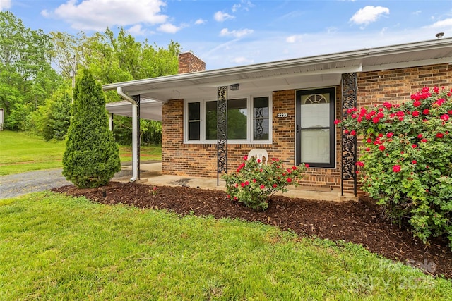 exterior space featuring a chimney, a front lawn, brick siding, and covered porch