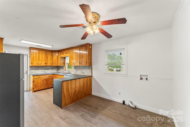 kitchen with freestanding refrigerator, baseboards, light wood-style flooring, a peninsula, and brown cabinetry