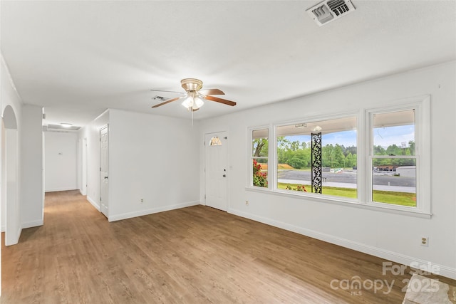 empty room featuring ceiling fan, baseboards, light wood finished floors, and visible vents