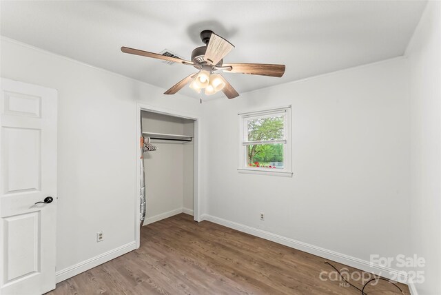unfurnished bedroom featuring wood finished floors, baseboards, a closet, and a ceiling fan