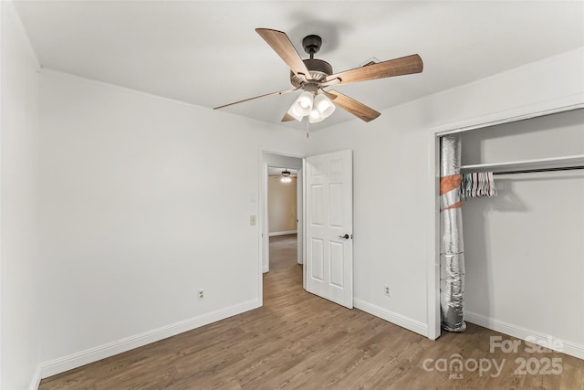 unfurnished bedroom with baseboards, a ceiling fan, wood finished floors, and a closet