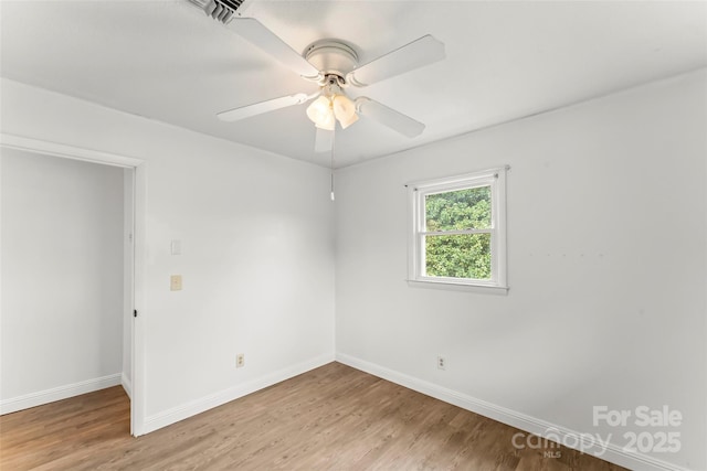 empty room featuring light wood finished floors, baseboards, and ceiling fan