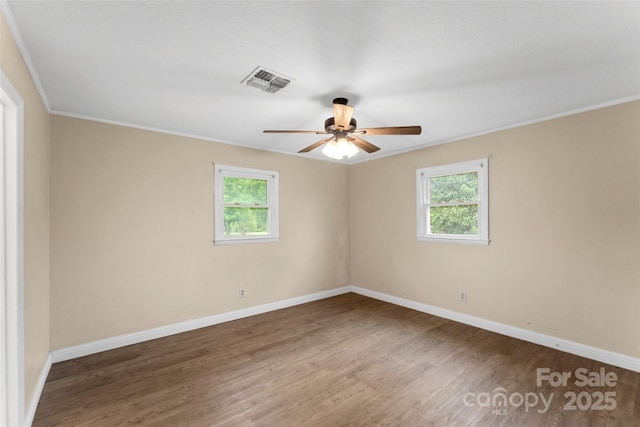 empty room with visible vents, wood finished floors, ceiling fan, and a healthy amount of sunlight