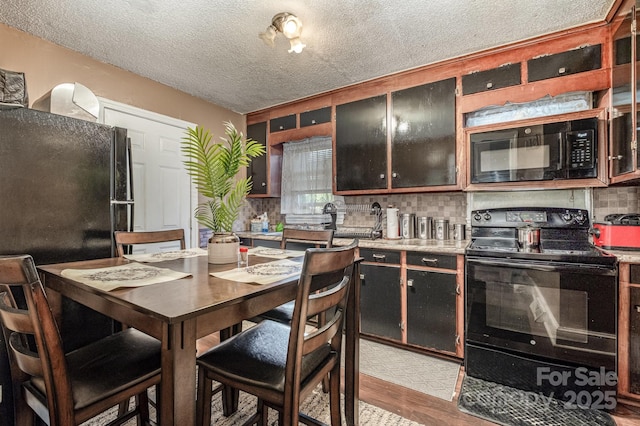 3919 Sarah Dr Unit 14, Charlotte, NC 28217 - kitchen with black appliances, tasteful backsplash, a textured ceiling, and light wood finished floors