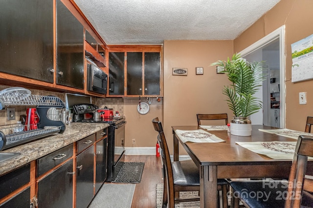 3919 Sarah Dr Unit 14, Charlotte, NC 28217 - interior space with dark brown cabinets, wood finished floors, baseboards, black appliances, and a textured ceiling