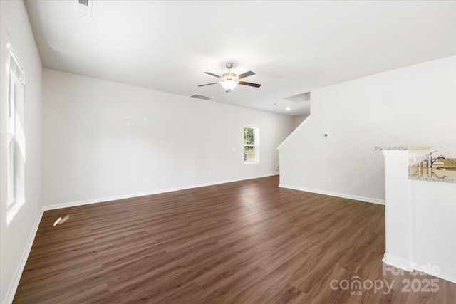 unfurnished room featuring a sink, dark wood finished floors, baseboards, visible vents, and ceiling fan