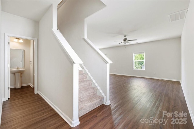 stairs featuring wood finished floors, visible vents, baseboards, and ceiling fan