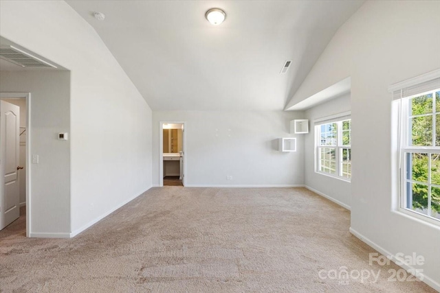 empty room featuring lofted ceiling, carpet floors, visible vents, and baseboards