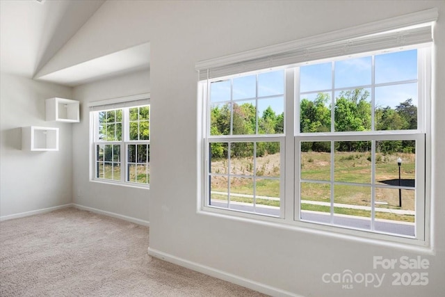 carpeted empty room with baseboards and lofted ceiling