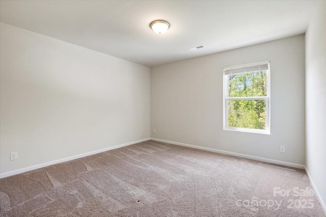 empty room with visible vents, baseboards, and carpet
