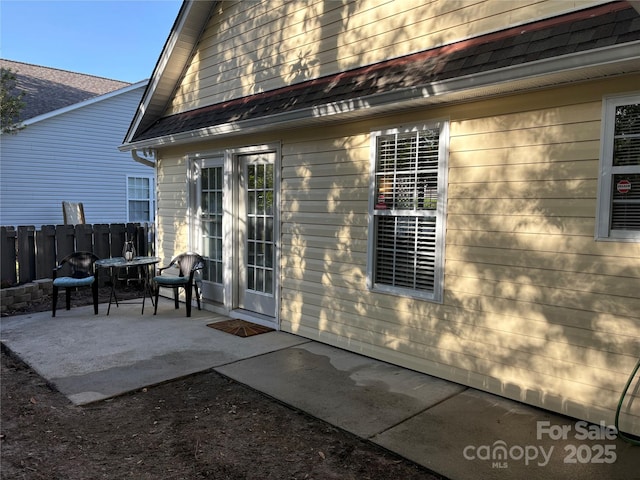 back of house featuring roof with shingles, fence, and a patio area