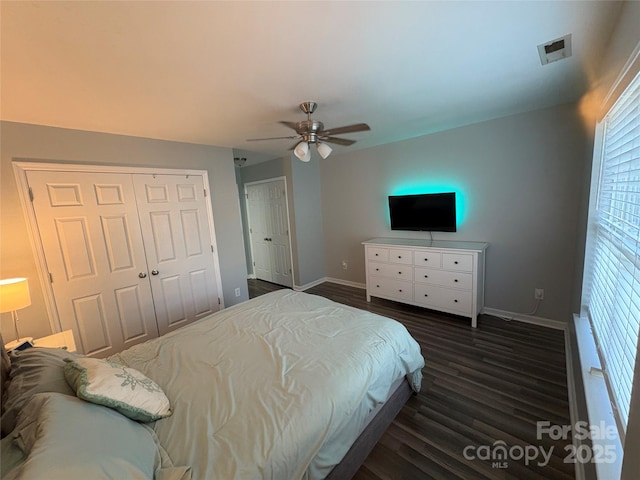 bedroom featuring dark wood-style flooring, visible vents, baseboards, a ceiling fan, and a closet